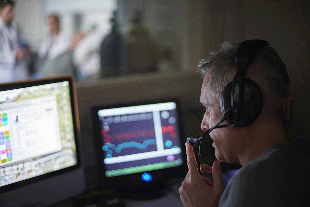 man concentrating on screens with headset