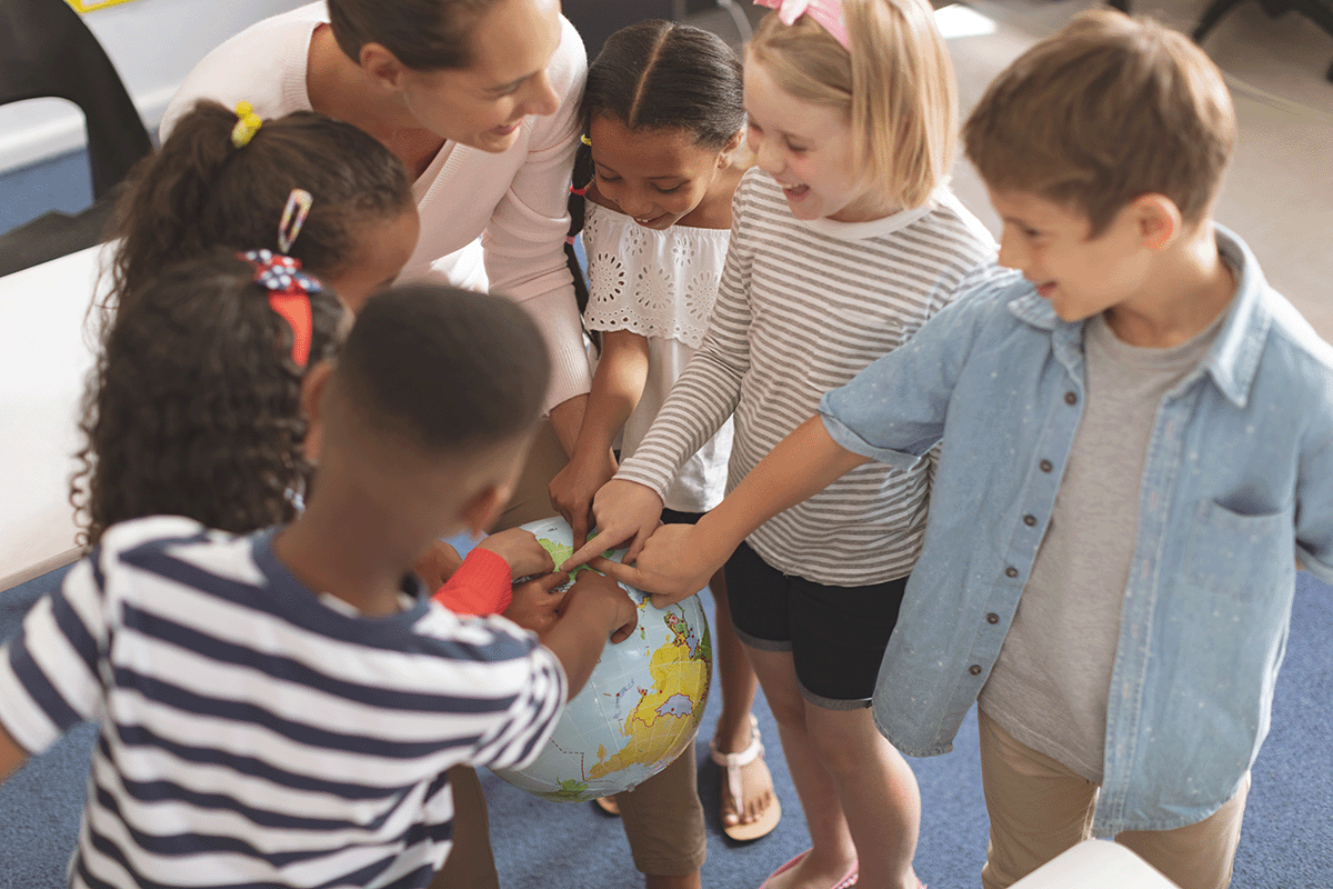 school children gathered around a globe with teacher