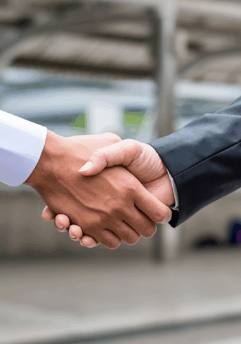 A close-up of two people shaking hands under dramatic blue lighting, signifying collaboration and agreement.