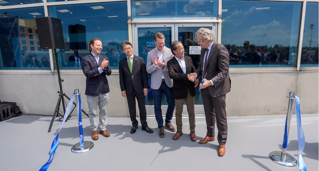 Leaders stand together and applaud during the Nissha ribbon-cutting event on Vanderbilt’s campus.
