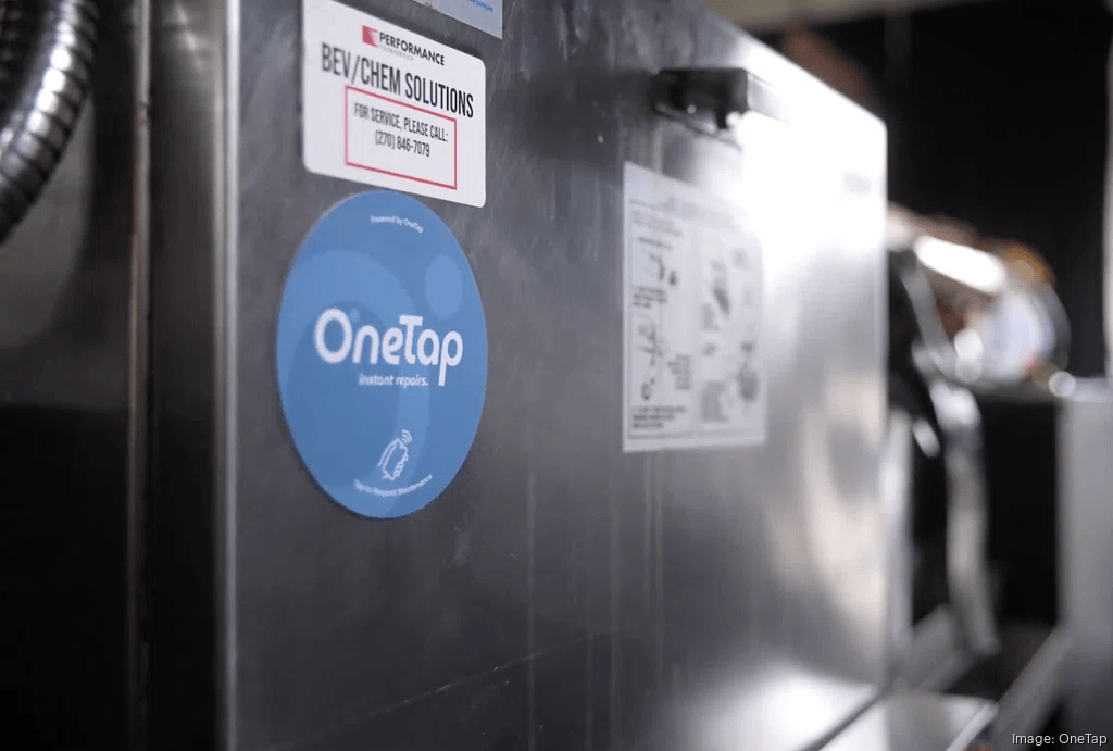 Close-up of industrial equipment displaying a OneTap instant repairs sticker and service labels. Image: OneTap.