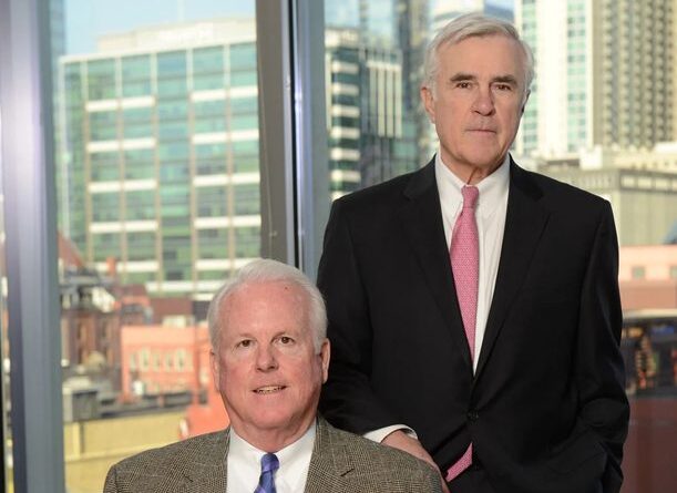 Terry Turner and Rob McCabe pose together in front of windows overlooking downtown Nashville.