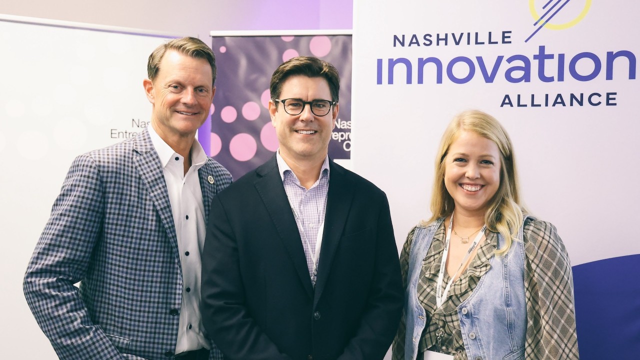 Stuart C. McWhorter, Nathan Buttrey and Lyndi Berrones pose together in front of Nashville Innovation Alliance signage.